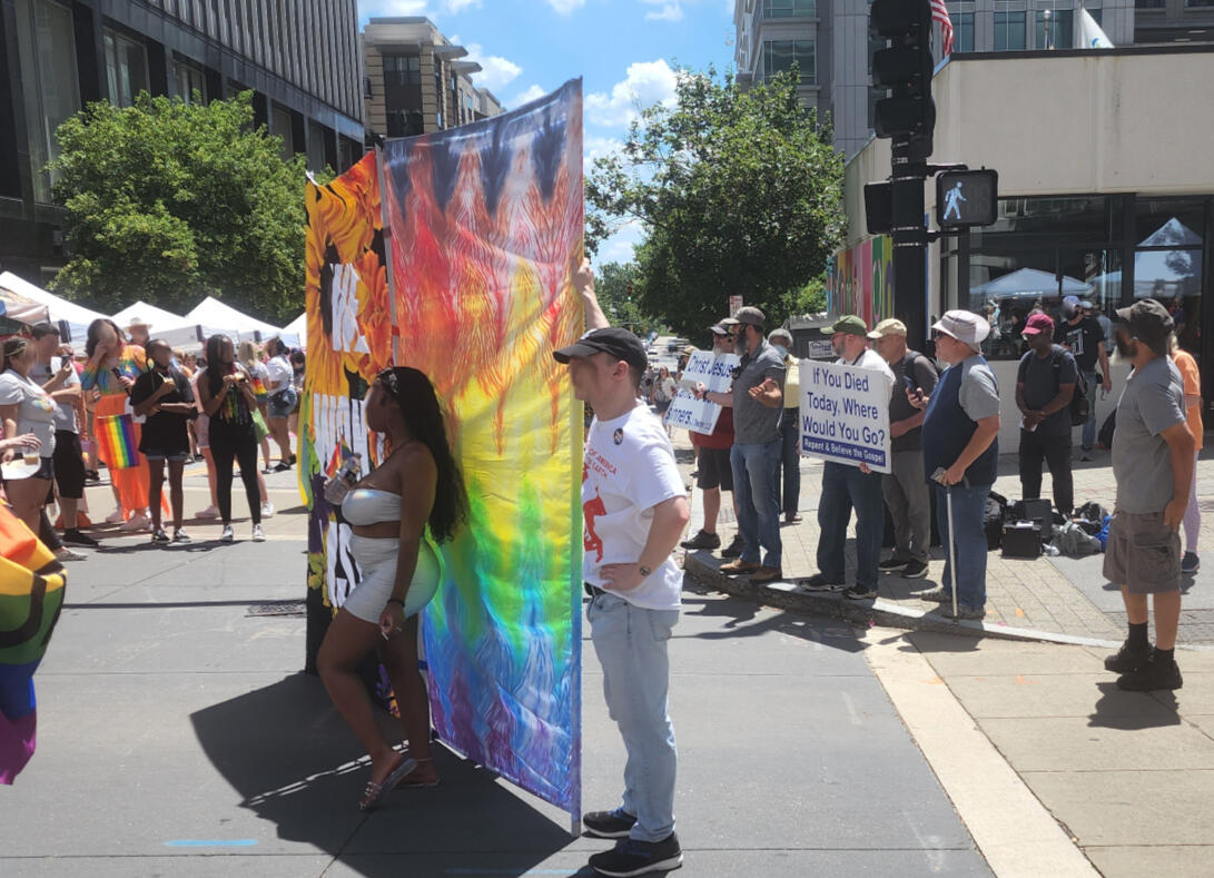 I love this photo - an attendee, posing and feeling (I hope) powerful; art created by local, LGBTQIA+ artists for the purpose of empowering our community, held by volunteers from a local church; and a bunch of failed protestors!