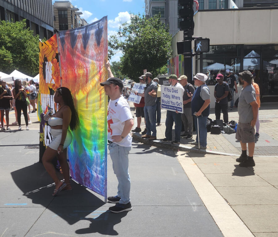 A pile of laminated paper signs, three of which show artist's statements for individual works, and one of which is an overall explanation of the project. a photo of all three current barriers is the background
